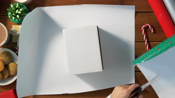 Hands Wrapping Christmas Gift Into Paper at Home