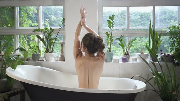 Woman with naked back sitting in the bathtub