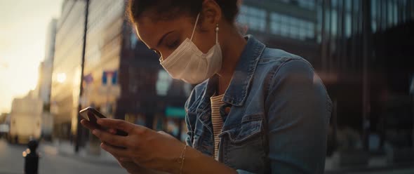 Video of woman in protective mask sitting with phone outdoors. Shot with RED helium camera in 8K.