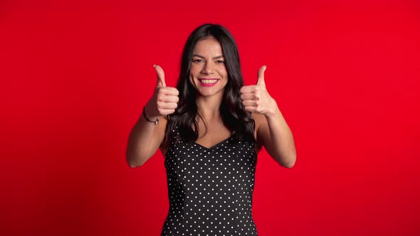 Young Latin Woman in Dress with Perfect Make-up Making Thumbs Up Sign Over Red
