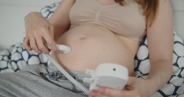 Young Pregnant Woman Using Pocket Ultrasound Doppler to Check Baby Heart Rate