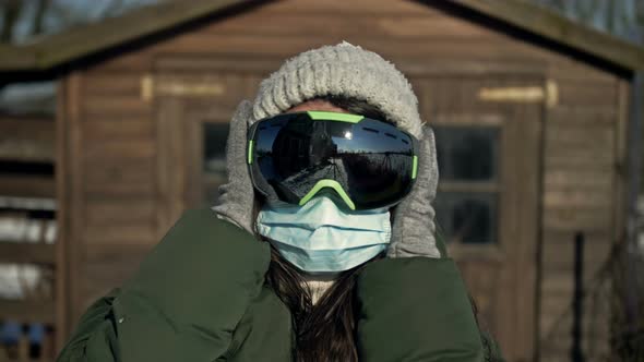 Portrait of a Young Woman Wearing Ski Goggles and a Medical Mask During the COVID19 Coronavirus on a