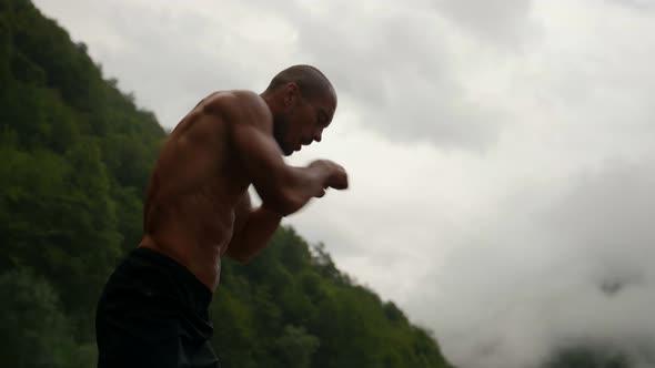 Professional Boxer or Fighter is Training Alone in Nature Striking to Air Practicing Hand Punch