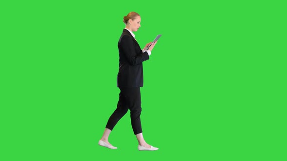 Beautiful Young Business Woman Walking and Using Digital Tablet on a Green Screen Chroma Key