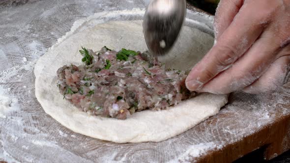 Chef make meat pies kutaba or chebureki, raw minced meat with onions and herbs filling dough.