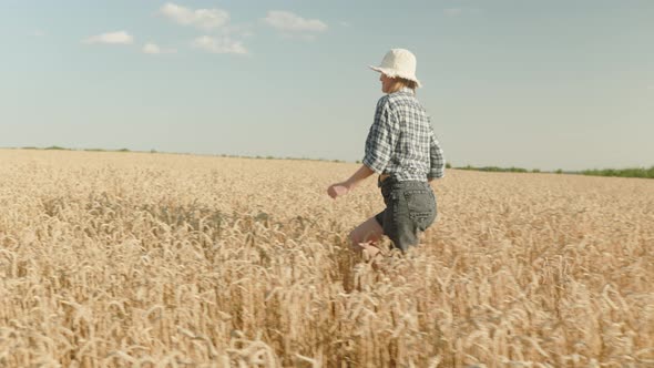 woman runing fun across the wheat field. agriculture dream concept. girl farmer hands to sides runs