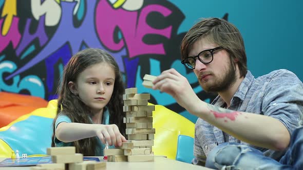 Young Man Father Teaches Smiling Child Girl, Playing Board Game