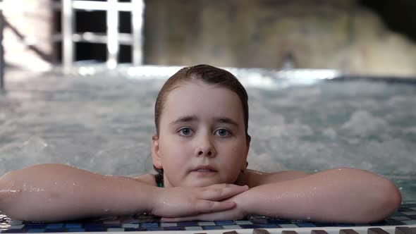 Little Girl in Waterpark Lying in Pool with Bubbling Water