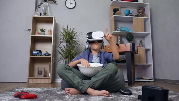 Smart Teen Boy which Sitting on Inflatable Armchair, Watching Video Using Virtual Reality Headset