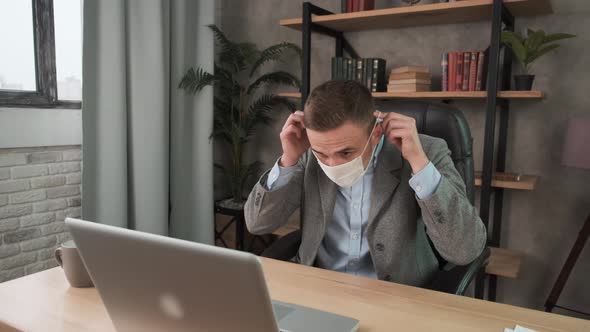 Young Businessman Wearing Protection Mask Face in the Office, Working Remotely at Home. Work During