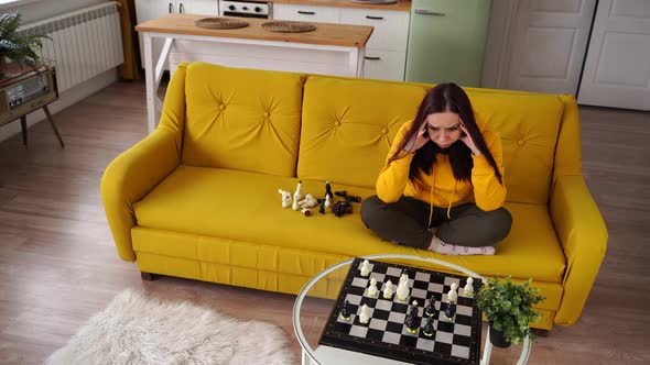 Young Upset Woman Playing Chess Sitting on Sofa