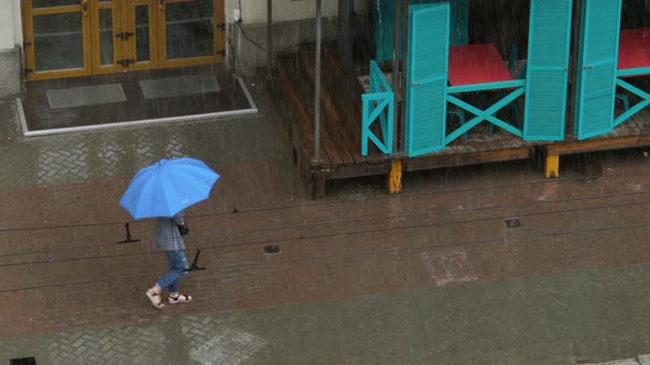 Woman Walk Under Heavy Rain with Blue Umbrella. Flood Disaster After Heavy Rain