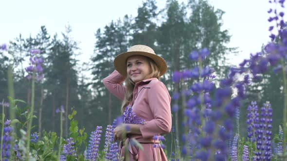 Attractive Woman in Dress Hat Stands in Field of Lupins Looks Up, Feminine Mysterious Girl