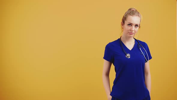Proud Young Caucasian Female Paediatrician Doctor Wearing Blue Uniform with Stethoscope Over Her