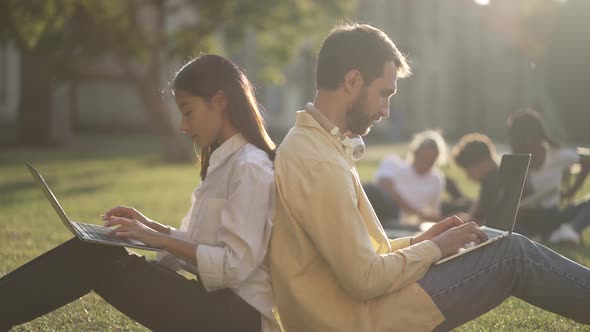 Diverse Mates Studying While Sitting on Green Lawn