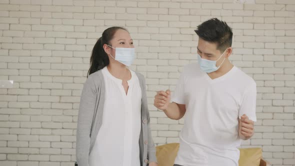 husband and wife laughing with a medical face mask funny dancing together