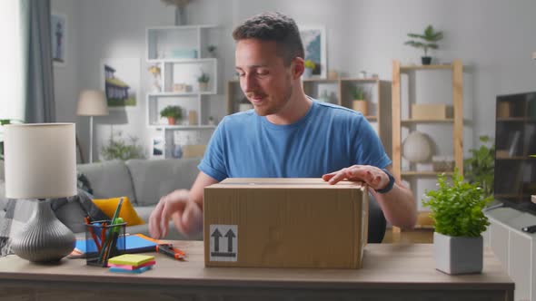 A Handsome Young Man Enters His Living Room with a Cardboard Box