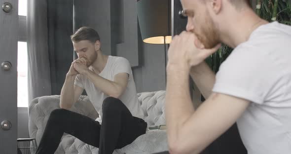 Reflection of Unhappy Young Handsome Man Sighing and Putting Head on Hands. Stressed Caucasian