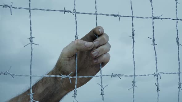 Dirty Man's Hand Grabs Barbed Wire Fence