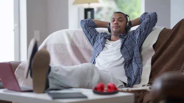 Wide Shot Portrait of Relaxed Thoughtful African American Man Sitting on Armchair in Home Office