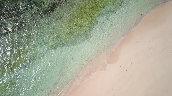 Aerial tracking shot of white sandy beach with crystal clear green waters and coral reefs in the Phi