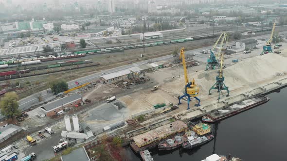 Industrial city part with river port and docks with yellow construction and cargo cranes