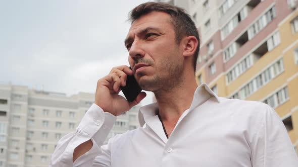 Closeup of a Frustrated Businessman in a White Shirt Talking on the Phone