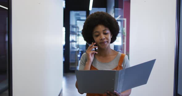 Mixed race businesswoman walking going through paperwork in modern office