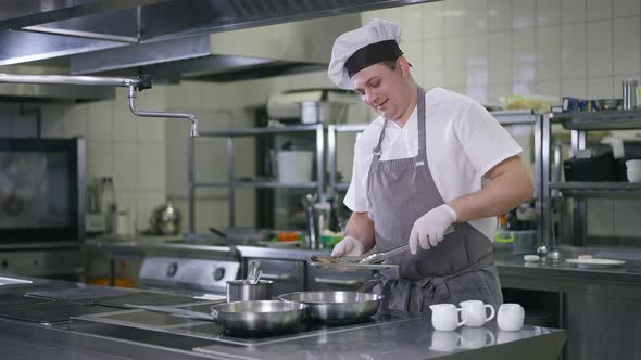 Cheerful Caucasian Chef Talking Smiling Putting Raw Shrimps on Cooking Pan in Restaurant Kitchen