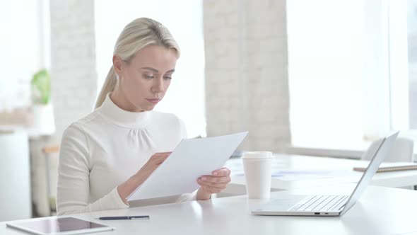 Successful Young Businesswoman Reading Documents in Office