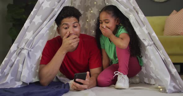 Happy biracial father and daughter using smartphone together