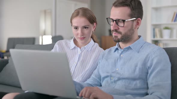 Excited Young Couple Celebrating Success on Laptop at Home 