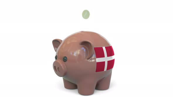 Putting Money Into Piggy Bank with Flag of Denmark