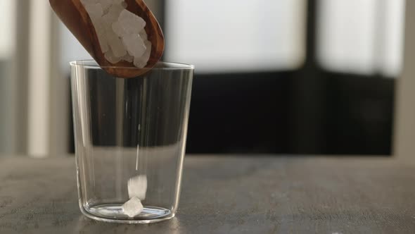 Slow Motion Fill Tumbler Glass with Crushed Ice on Oak Table with Copy Space