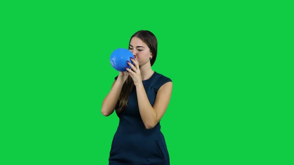 Girl blowing up a balloon in front of a green screen