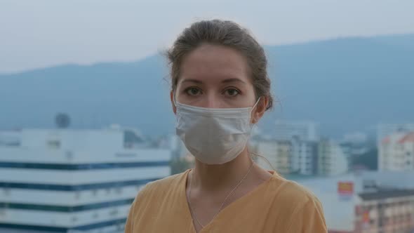 Portrait of a Beautiful Young Woman Wearing Protective Medical Face Mask and Standing on the Rooftop