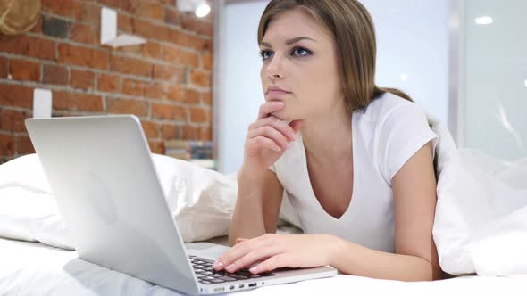 Thinking Pensive Woman Lying in Bed on Stomach, Brainstorming