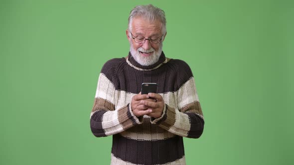 Handsome Senior Bearded Man Wearing Warm Clothing Against Green Background