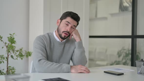 Sleepy Young Man Taking Nap While Sitting in Office