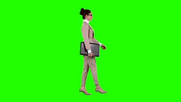 Girl Is Going To a Meeting with a Laptop in Her Hands. Green Screen. Side View. Slow Motion