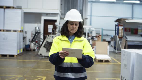 Serious Engineer Checking Equipment While Walking with Tablet