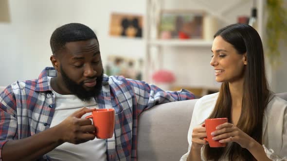 Young Mixed-Race Couple Drinking Coffee and Talking at Home, Nice Conversation