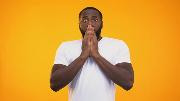 Young Surprised Black Man Closing His Mouth With Hands on Yellow Background