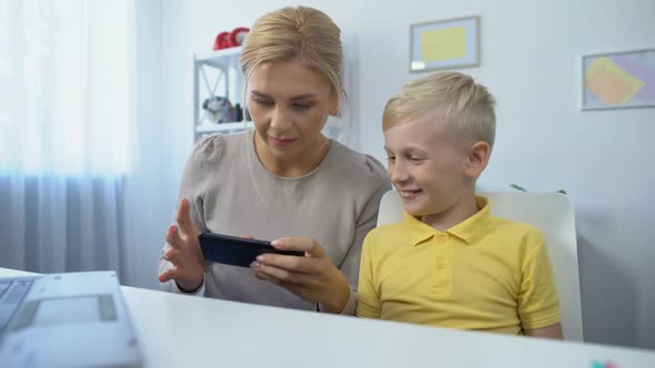 Happy Mother and Son Playing Games on Smartphone Together, Having Fun, App