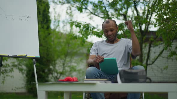 Front View of Excited African American Paraplegic Man Making Victory Gesture Rejoicing Ebusiness