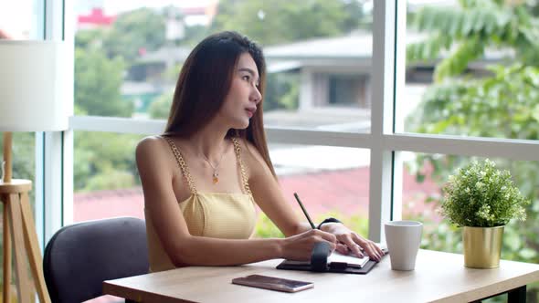 Young pretty woman writing in appointment book at coffee shop