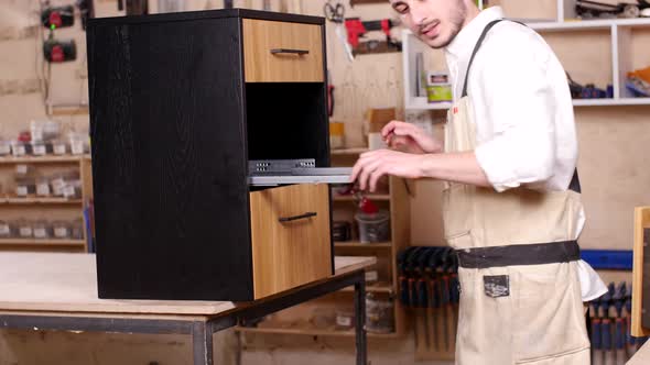 Concept of Business and Manufacture Young Man in the Workshop Assembles Furniture