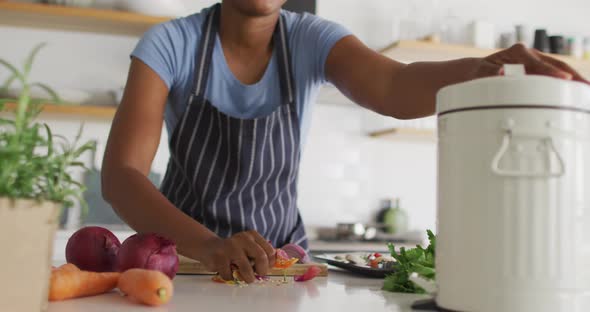 Happy african american woman cleaning waste in kitchen