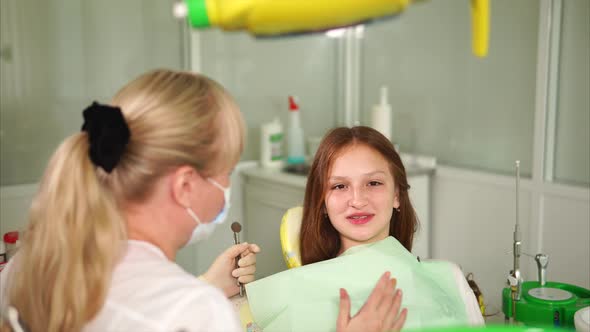 The Doctor of the Clinic Tells the Teenager About the Treatment of Oral Cavity
