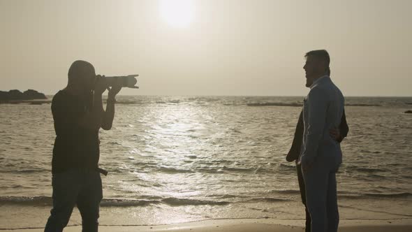 Photographer taking pictures of gay couple before their wedding on the beach